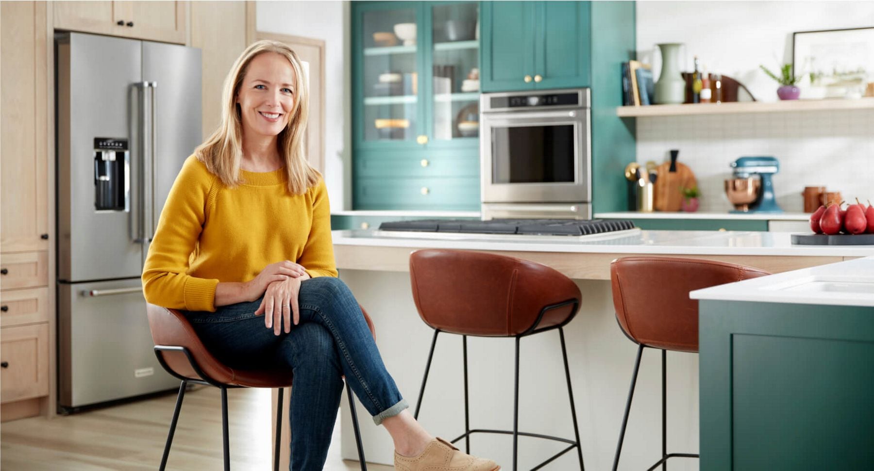 Tisha Johnson sitting in a modern, bright kitchen filled with KitchenAid® appliances.