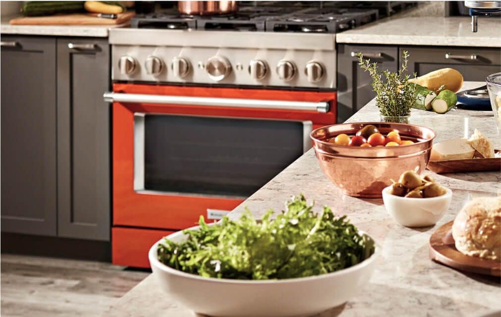 An island with bowls full of different ingredients with a KitchenAid® range in the background.