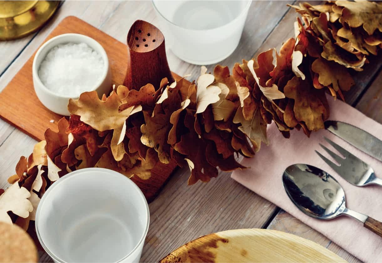 A stylish table decorated with seasonal leaves and place settings.