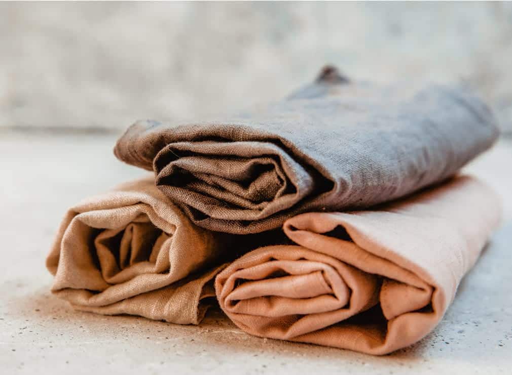 Linens in seasonal colors folded and stacked on top of one another.