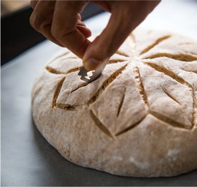 A person scoring an unbaked loaf of bread.