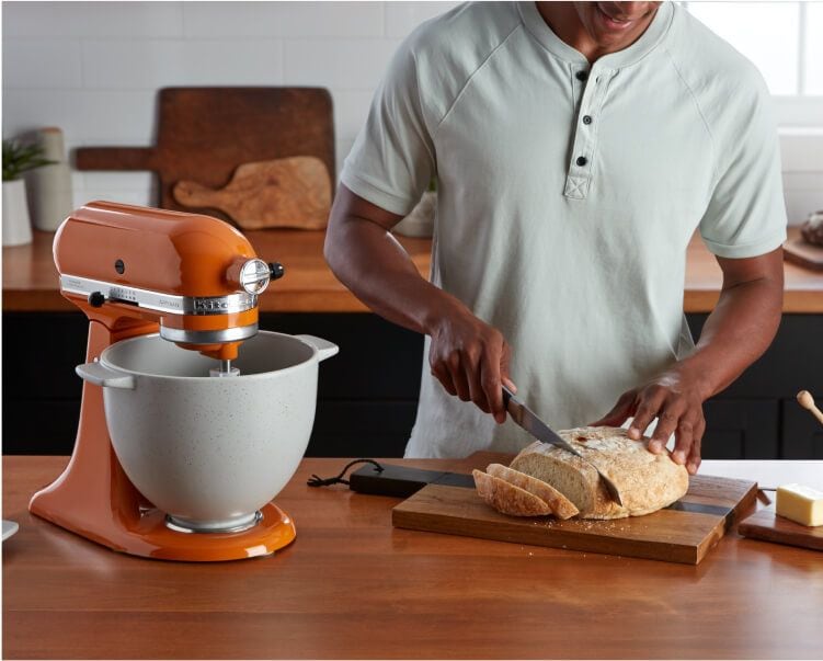 A person cutting fresh bread that was made with a KitchenAid® Stand Mixer.