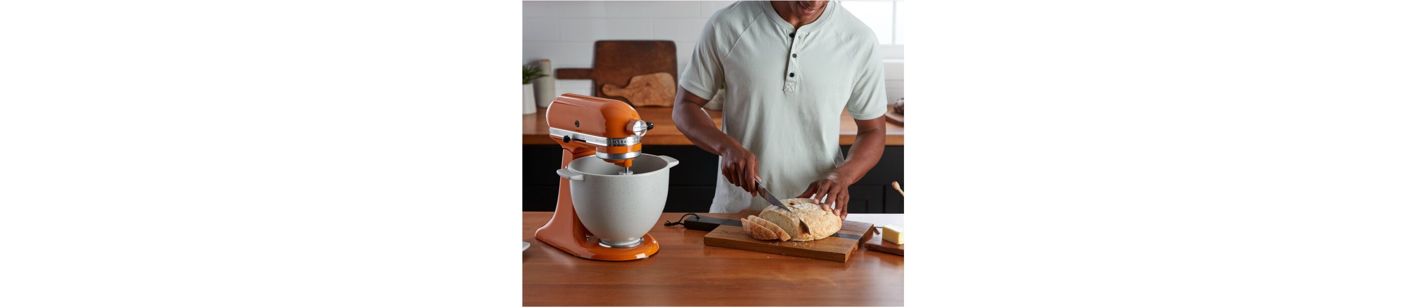 A person cutting fresh bread that was made with a KitchenAid® Stand Mixer.