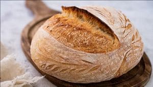 Freshly baked sourdough bread on a wooden serving board.