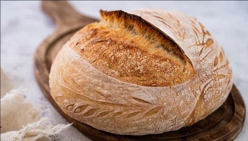 Freshly baked sourdough bread on a wooden serving board.