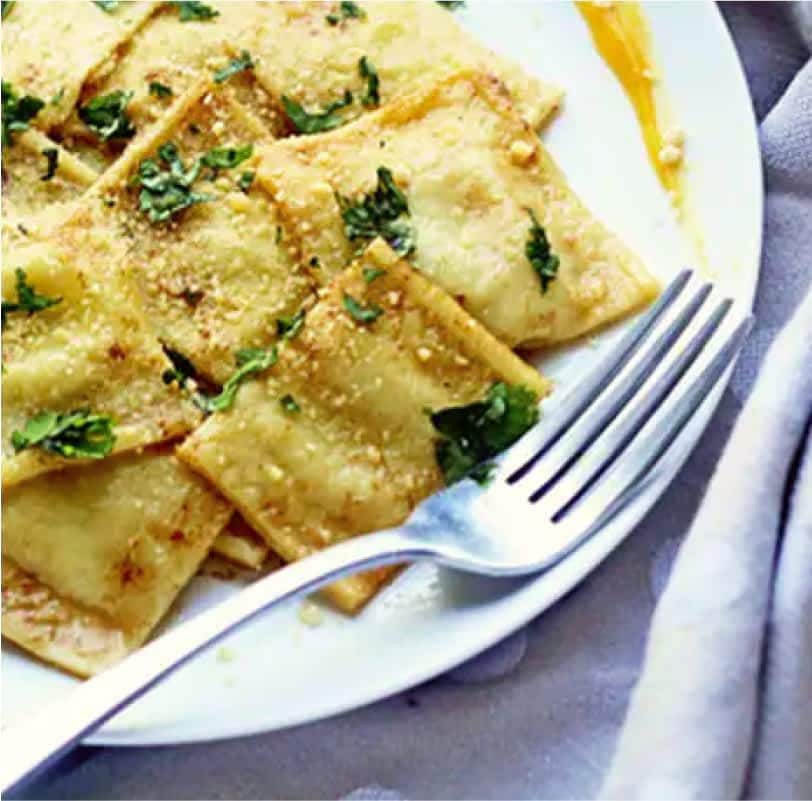 Butternut squash ravioli on a plate with a fork.