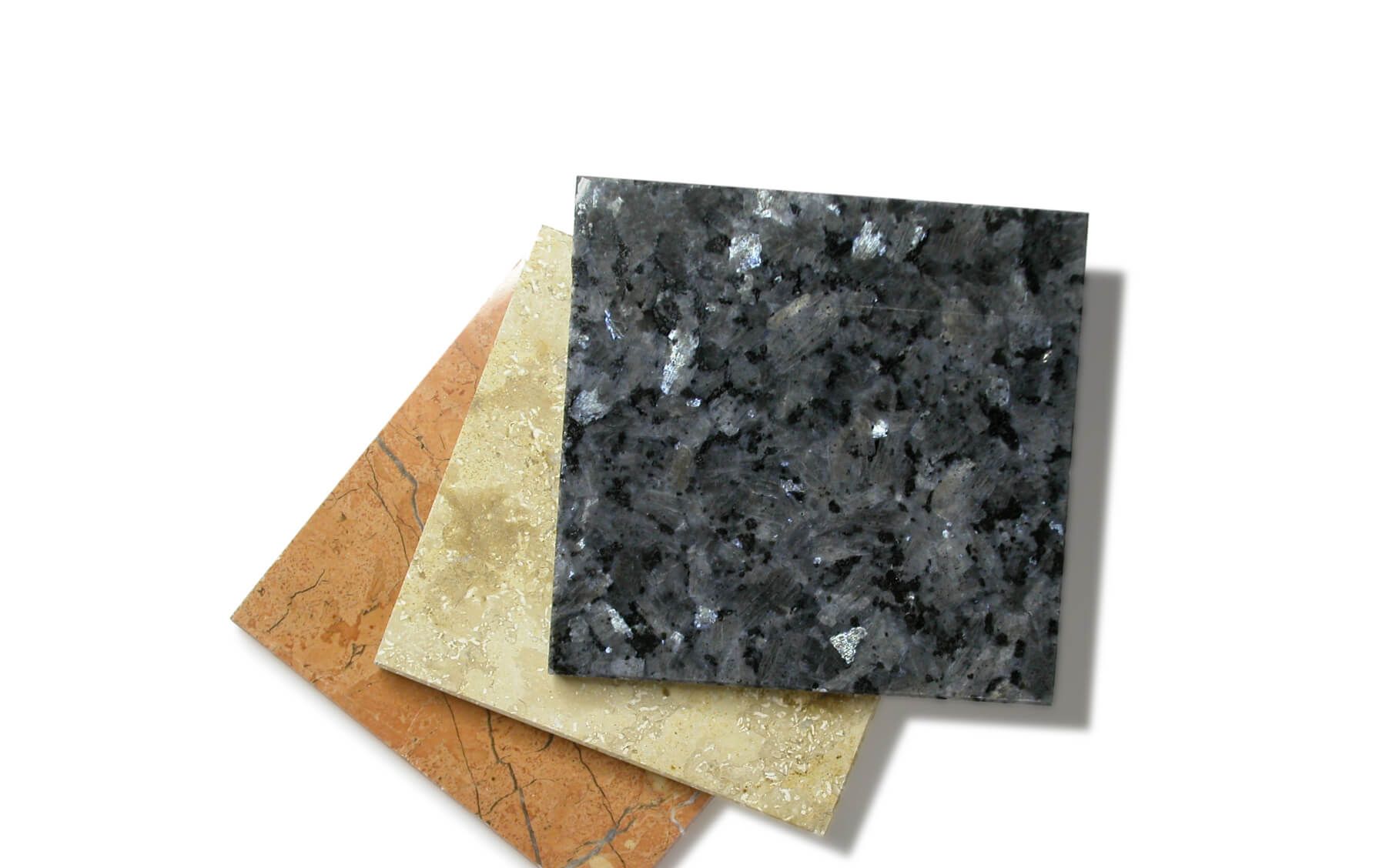 Three samples of stone for countertops including a clay, a tan and a dark grey color.