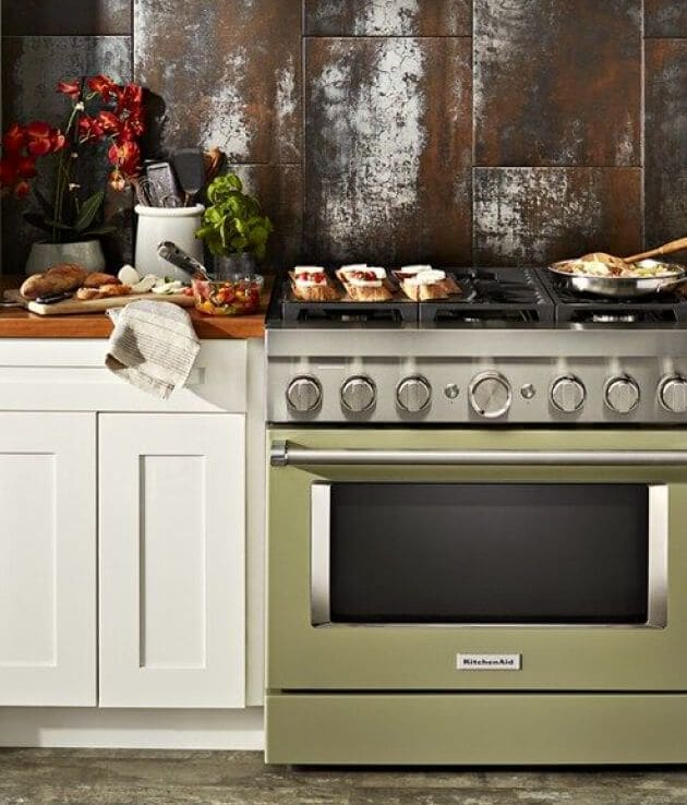 KitchenAid® Commercial-Style Range in Avocado Cream set in white cabinetry in front of copper colored wall.