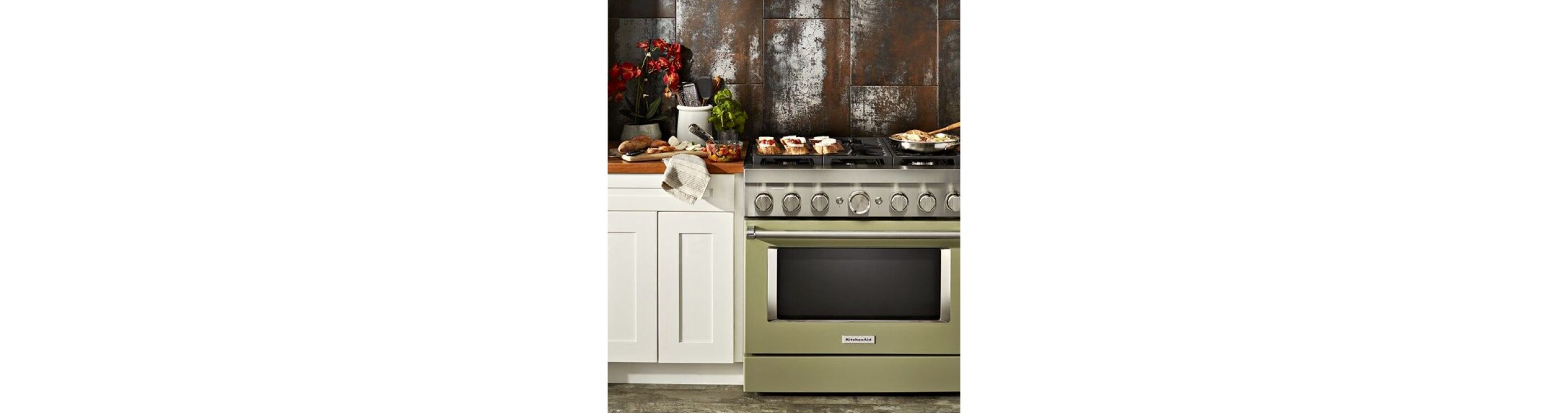 KitchenAid® Commercial-Style Range in Avocado Cream set in white cabinetry in front of copper colored wall.