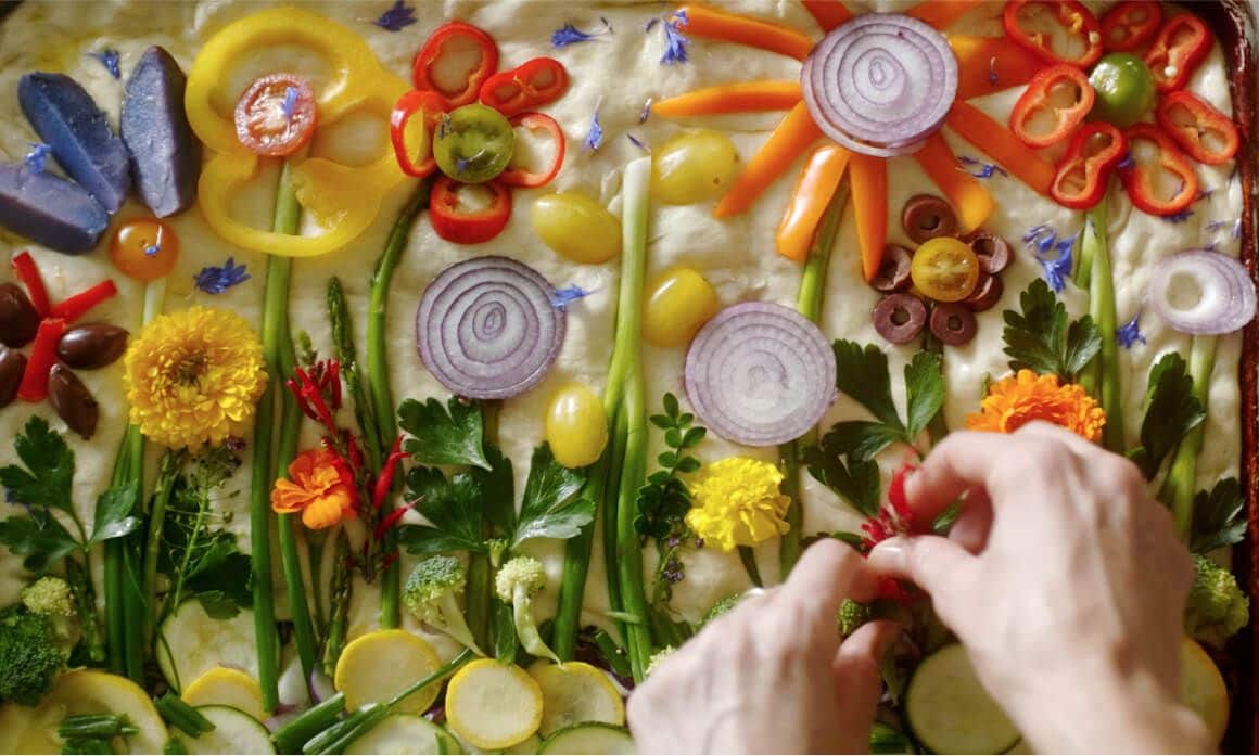 Focaccia bread dressed with edible flowers and other vegetables.