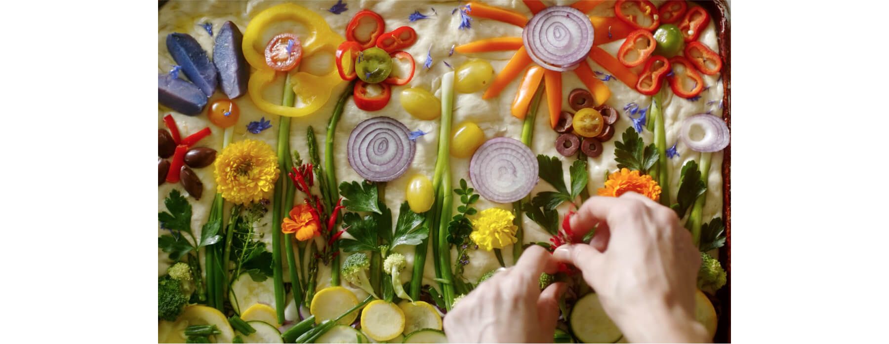 Focaccia bread dressed with edible flowers and other vegetables.