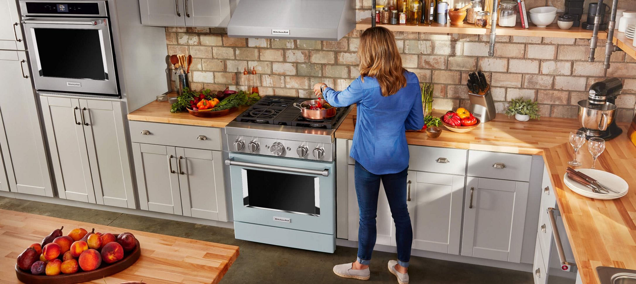A woman cooking on a range, her counter full of veggies.