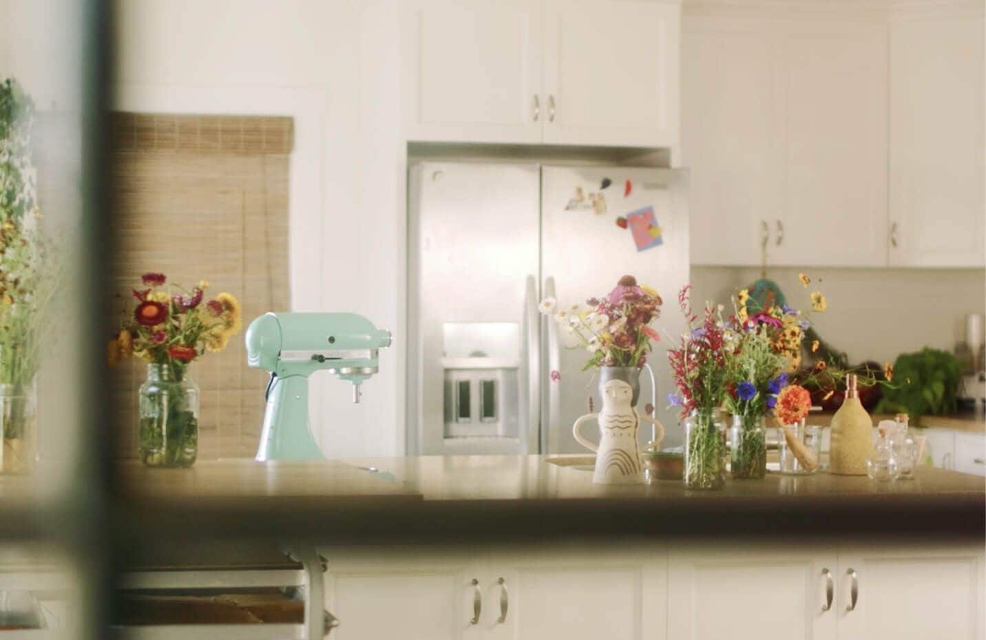 White kitchen with KitchenAid® French Door Refrigerator in stainless and island with KitchenAid® Stand Mixer in Aqua Sky