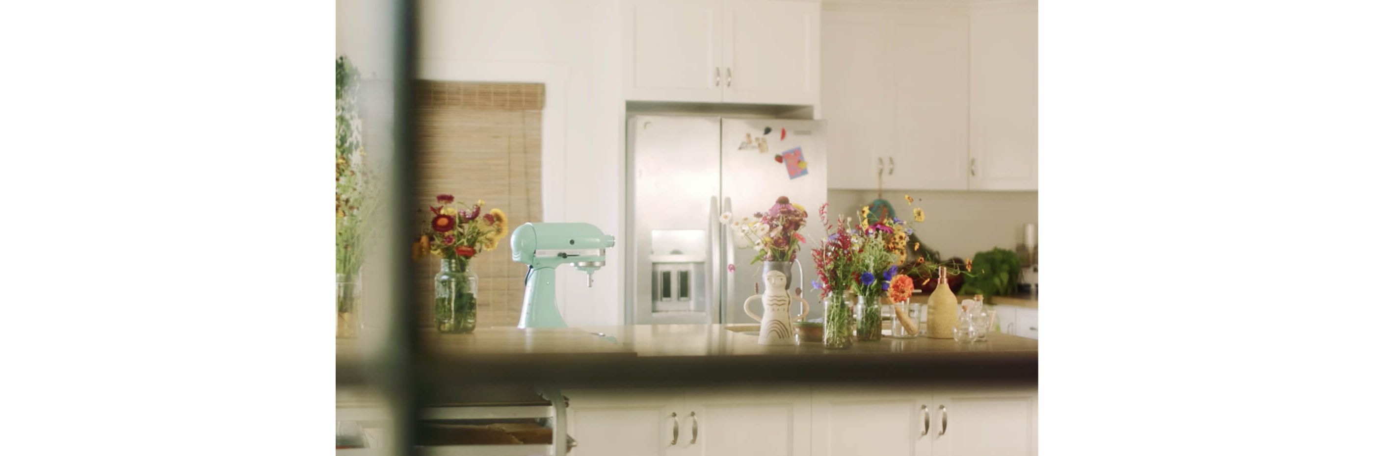 White kitchen with KitchenAid® French Door Refrigerator in stainless and island with KitchenAid® Stand Mixer in Aqua Sky