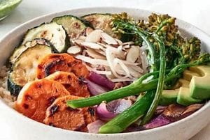 A Cauliflower Rice Bowl topped with colorful grilled vegetables.