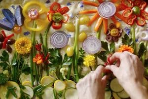 A variety of colorful vegetables and edible flowers arranged on Focaccia dough.