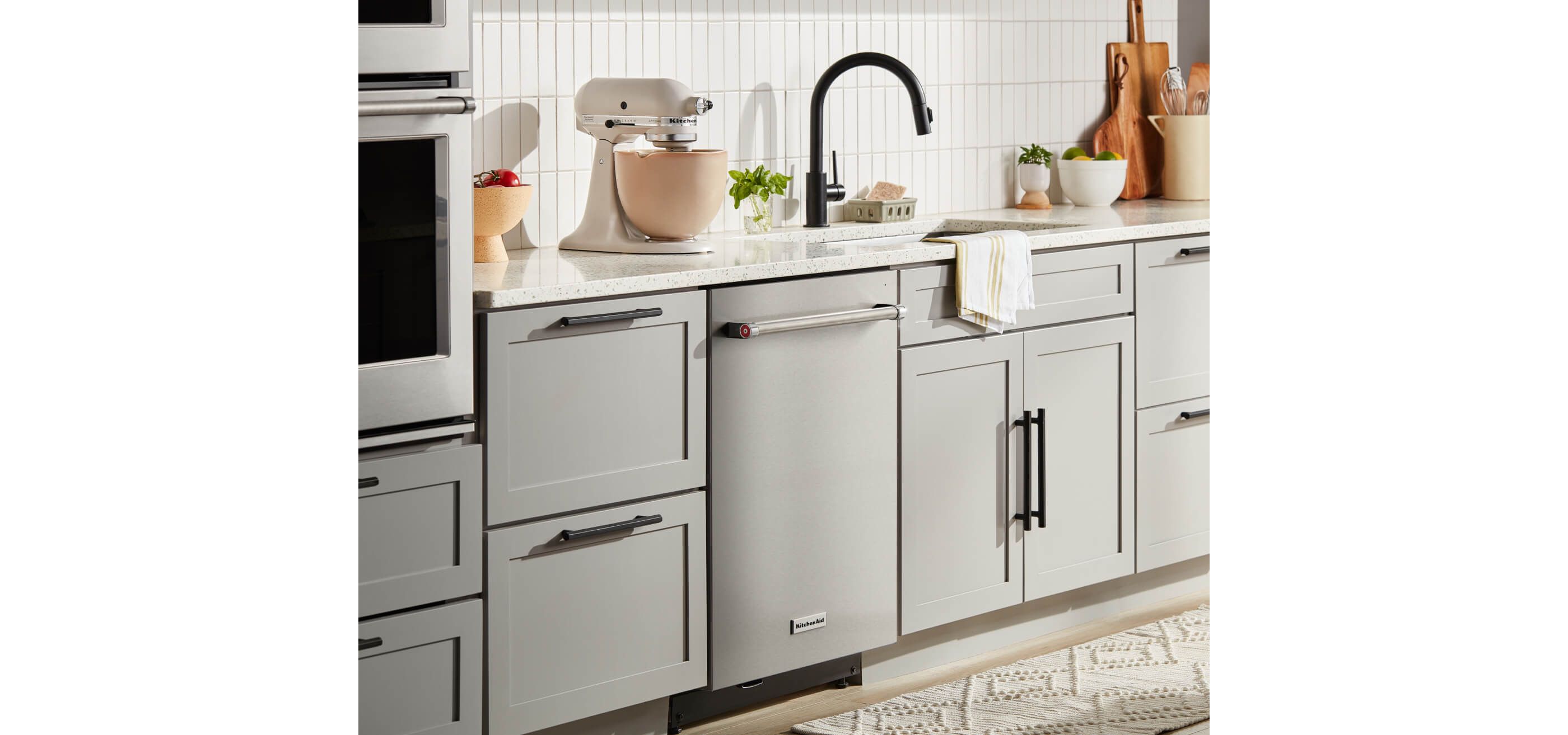 KitchenAid® Stand Mixer and ceramic bowl on countertop, dishwasher in stainless set in white cabinets.