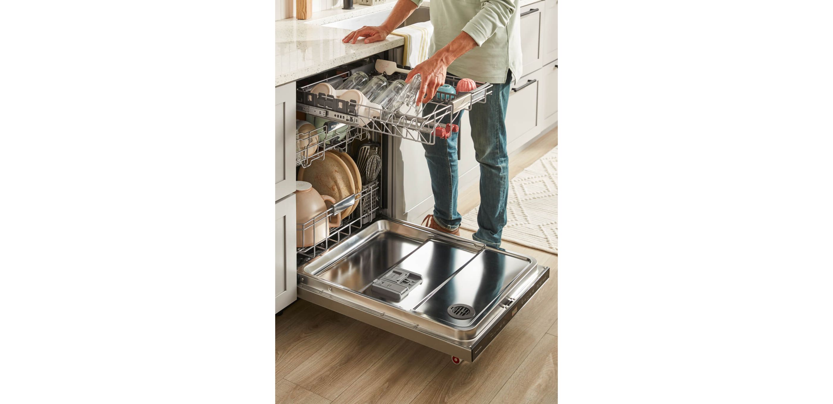 Man standing in front of KitchenAid® FreeFlex™ Third Rack dishwasher loading dishes onto upper rack.