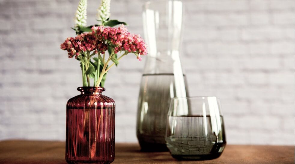 Pink flowers in amber vase next to two grey glass vases