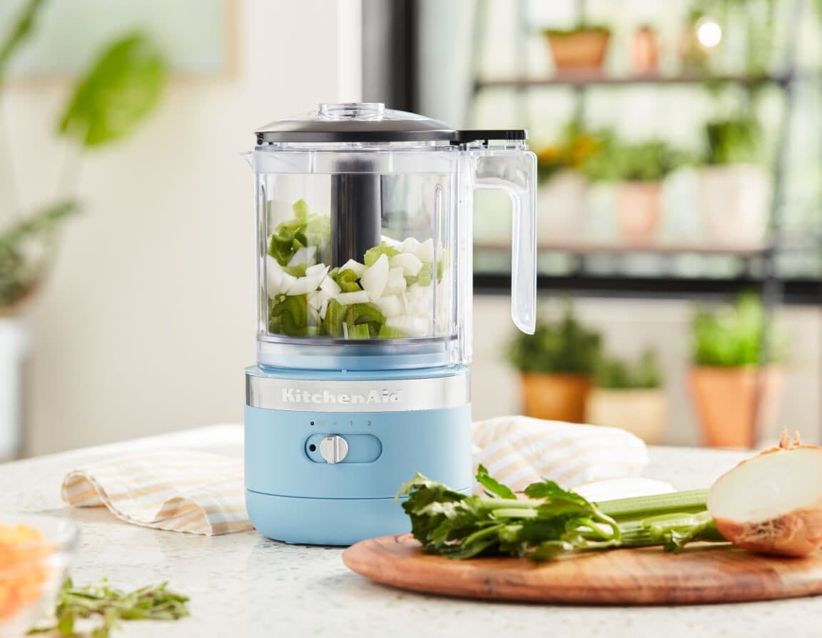 A Food Chopper in Blue Velvet holding chopped onions and celery.