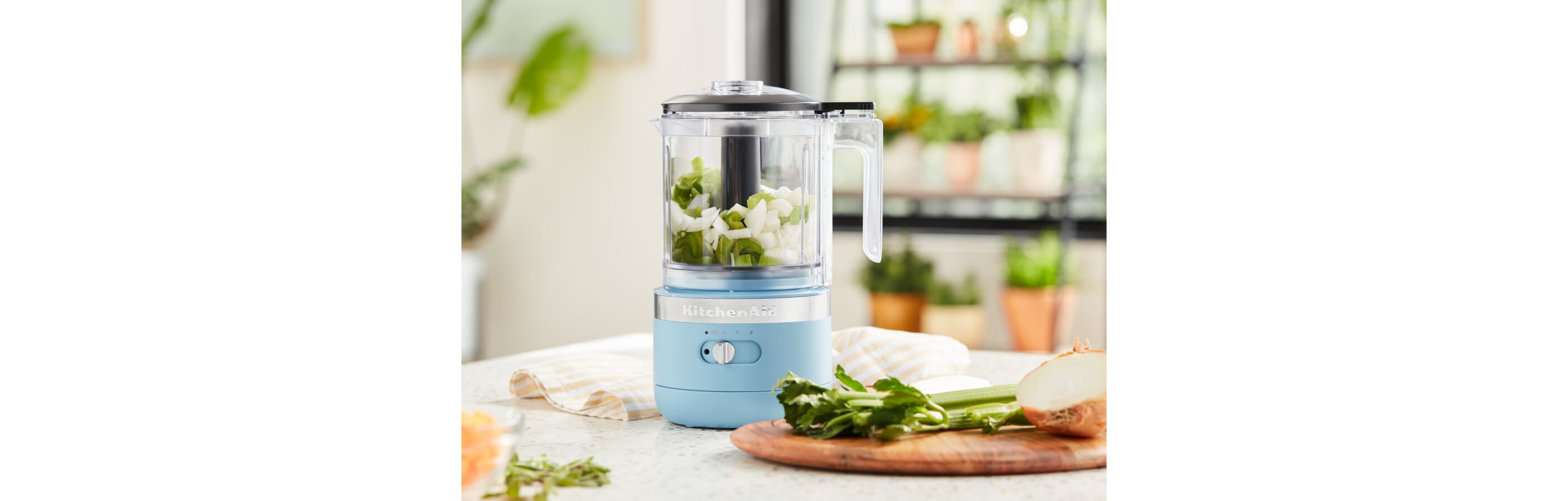 A Food Chopper in Blue Velvet holding chopped onions and celery.