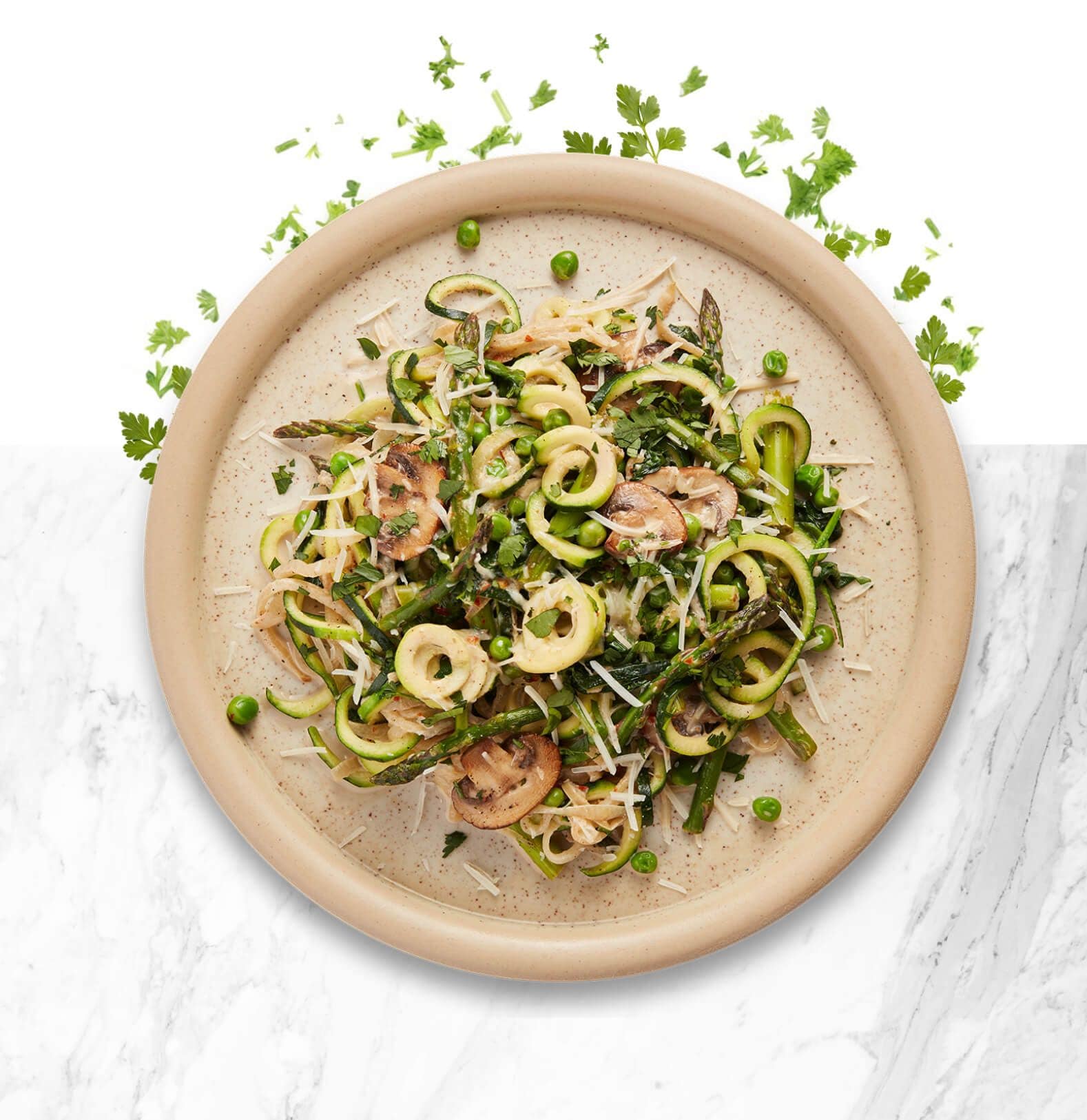 Earth tone colored bowl with zucchini noodles, mushrooms and fresh herbs.