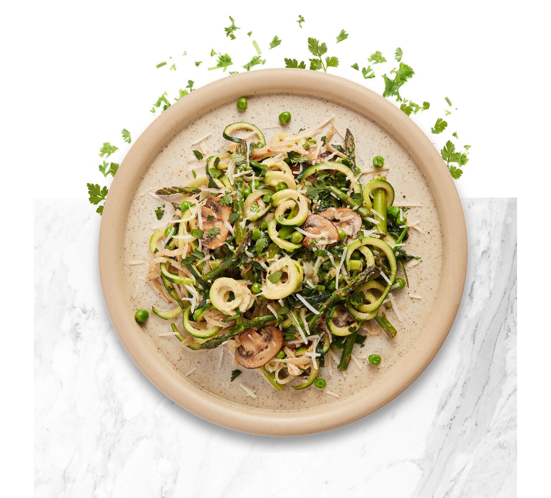 Earth tone colored bowl with zucchini noodles, mushrooms and fresh herbs.