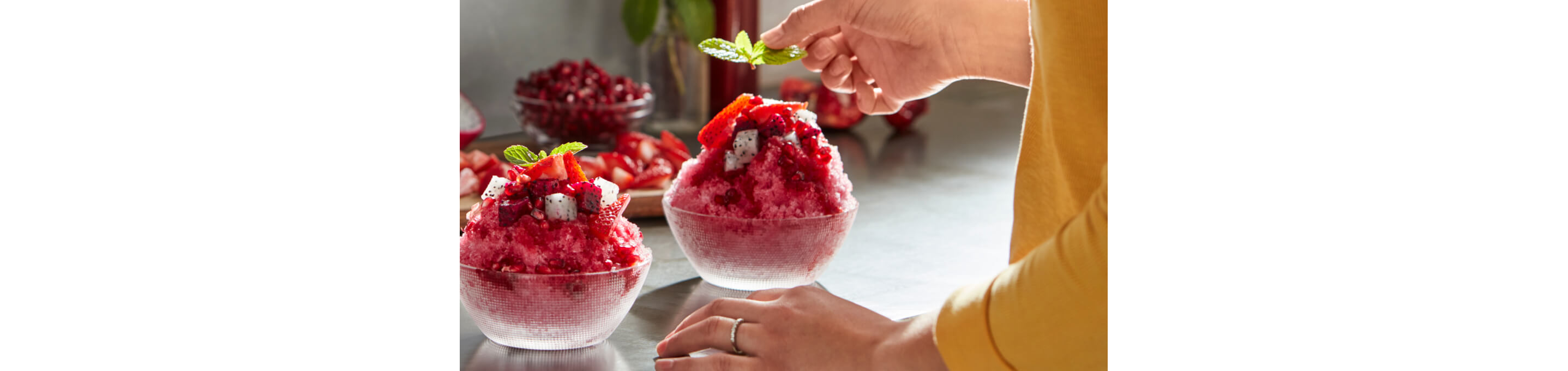 Shaved ice dessert garnished with fruit and mint.