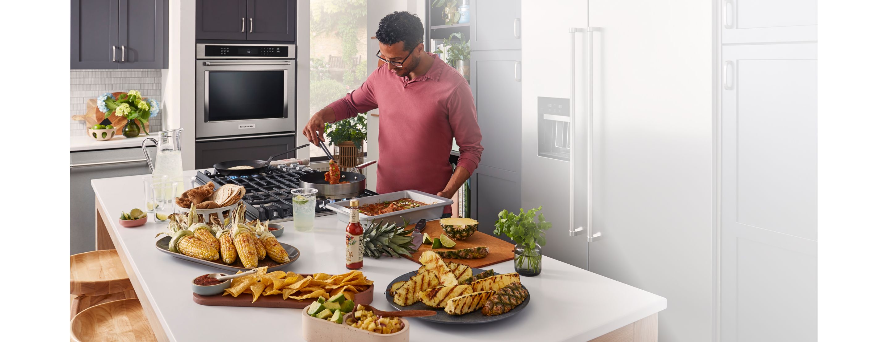A person preparing barbecue and tapas in a bright kitchen