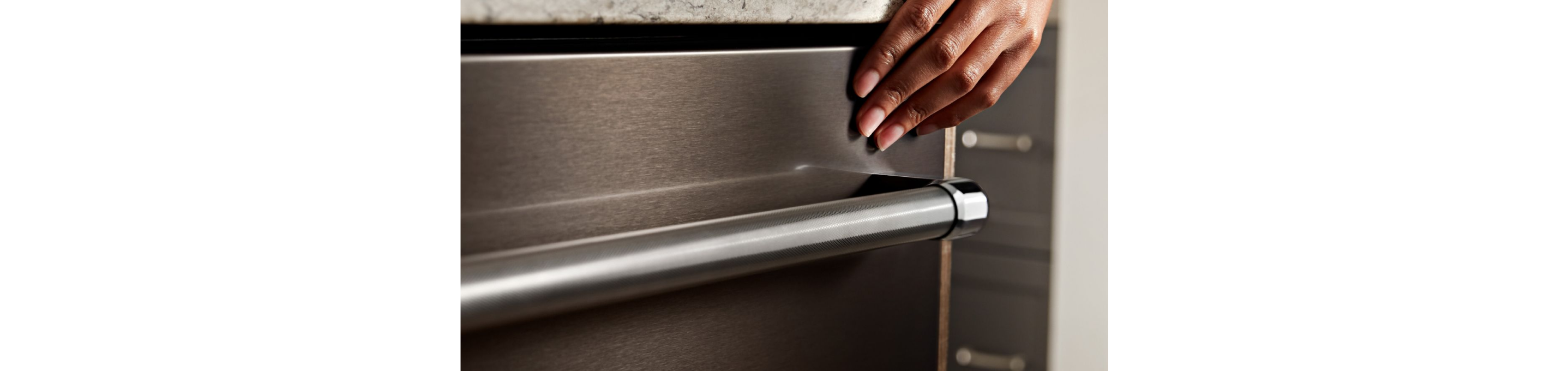 A person touching the exterior of a dishwasher.
