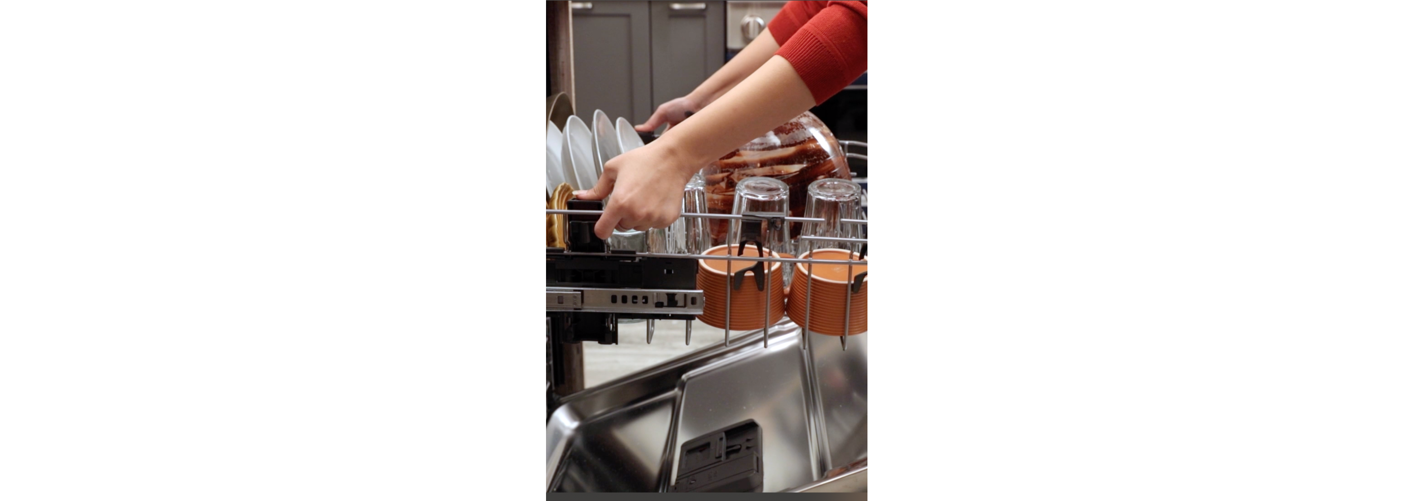 A person adjusting the middle rack of a dishwasher.
