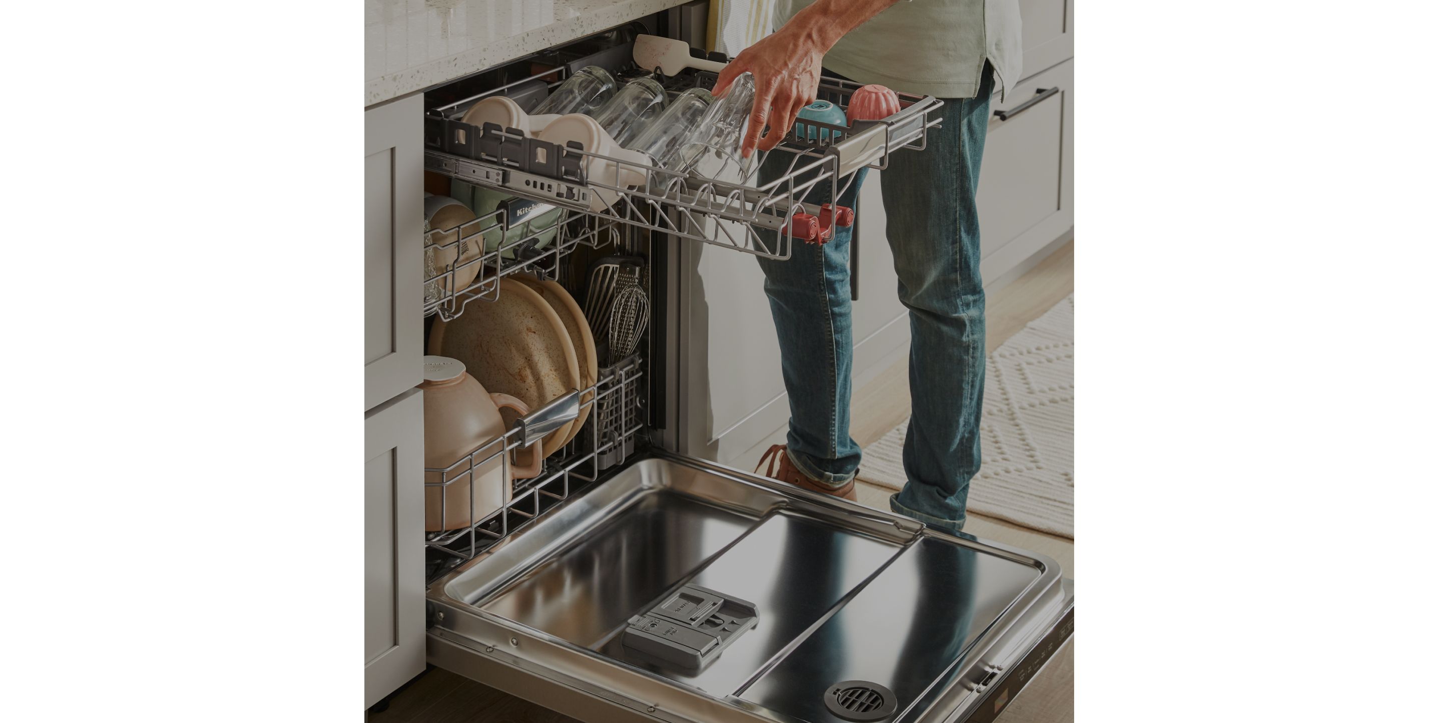 A person loading dishes into a KitchenAid® dishwasher.