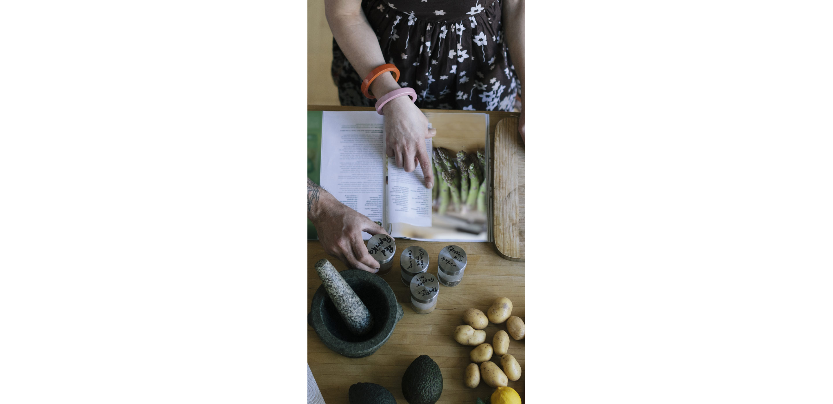 A woman reviewing an asparagus recipe with all of the required ingredients spread out on her table.
