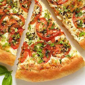 A close-up of a sliced artisan pizza on a clean, white plate.