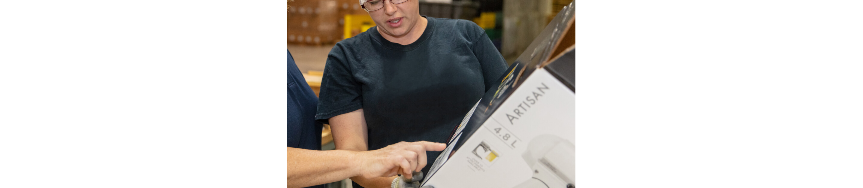 KitchenAid® technicians checking a refurbished appliance in new packaging.