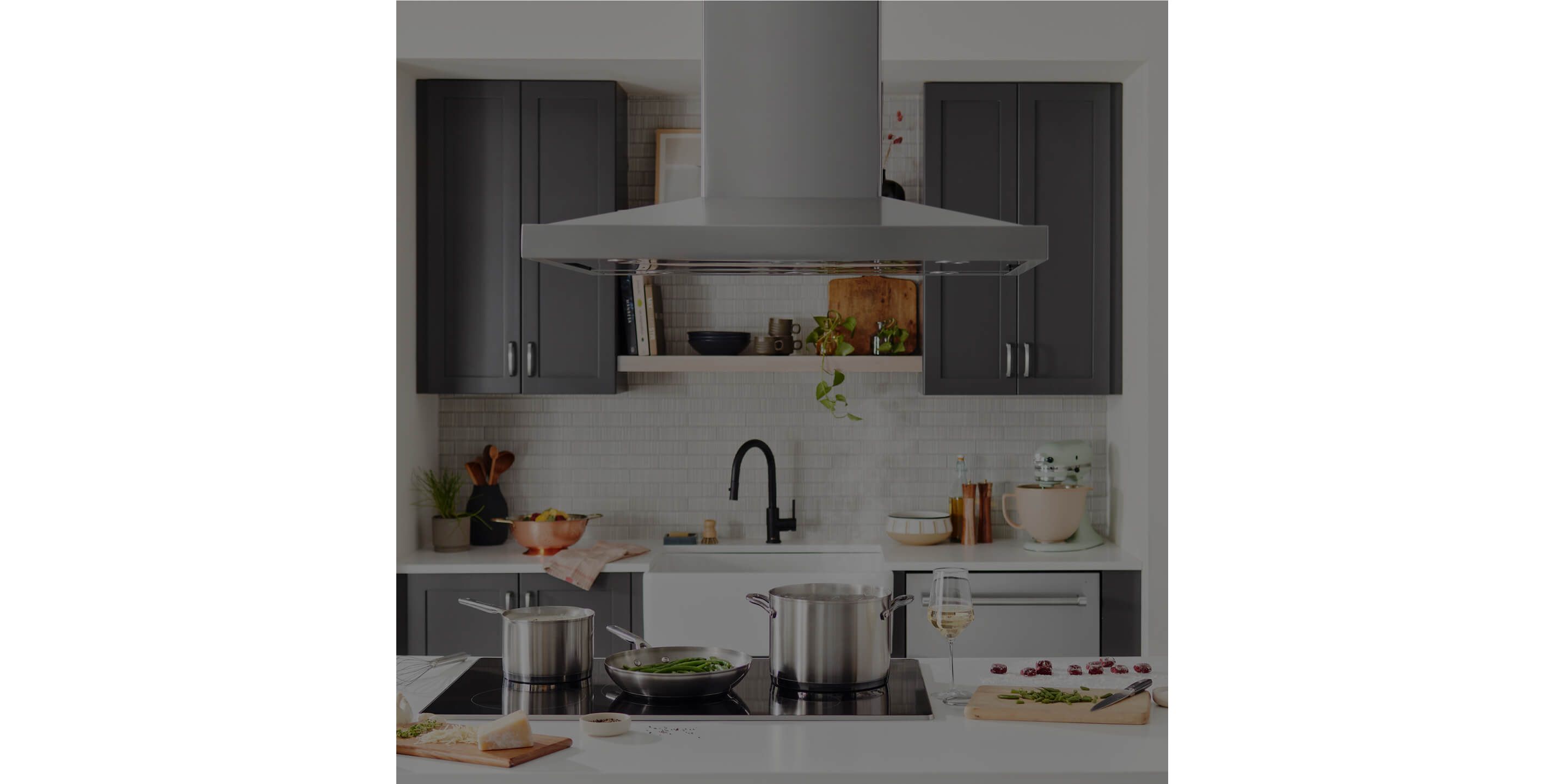 A KitchenAid® island hood above an induction cooktop.