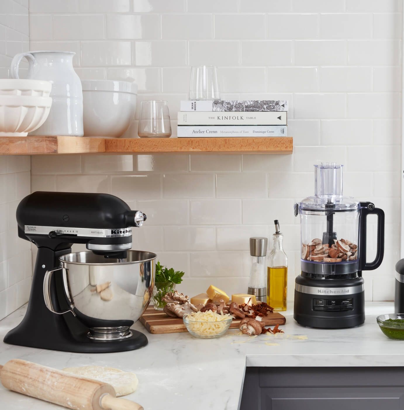 Profile shot of an organized countertop with stand mixer, blender, assorted fruits and plants.
