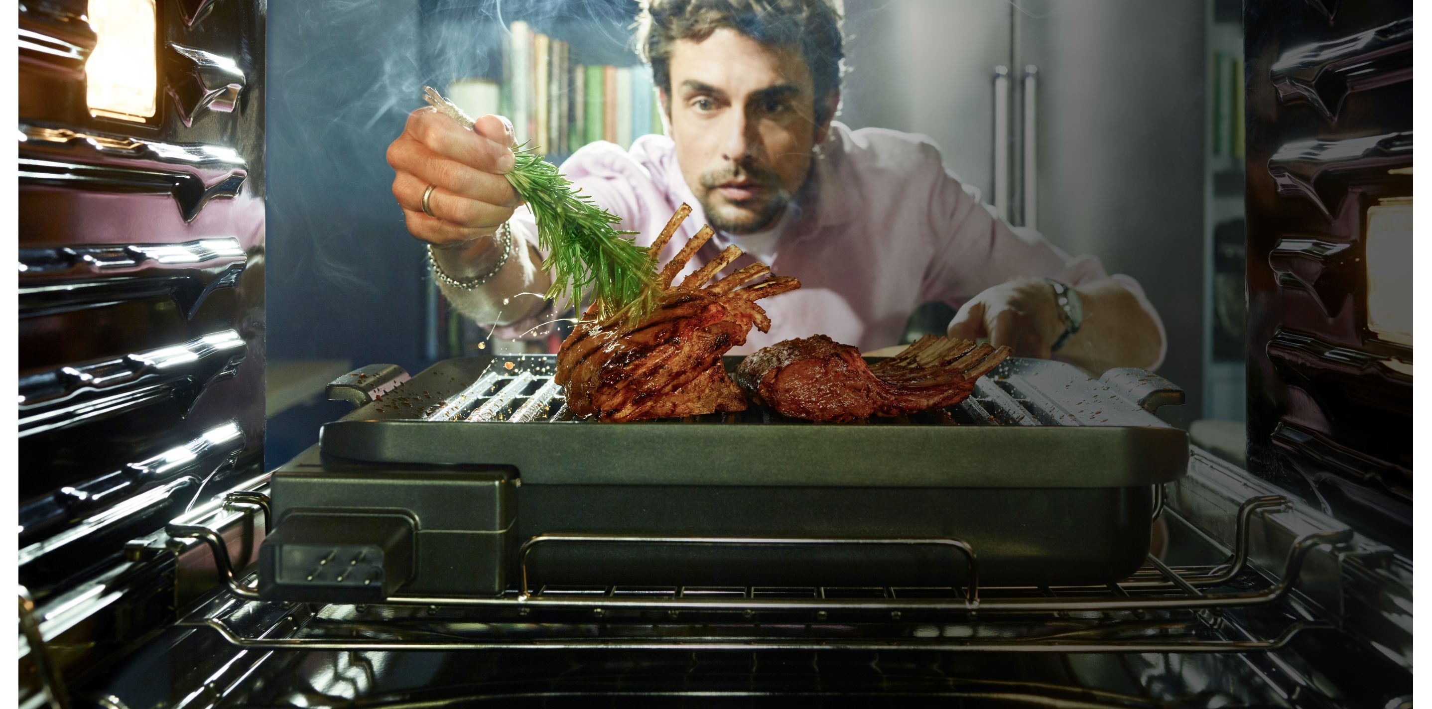 Man brushing a delectable roast with fresh rosemary, just coming out of the oven.