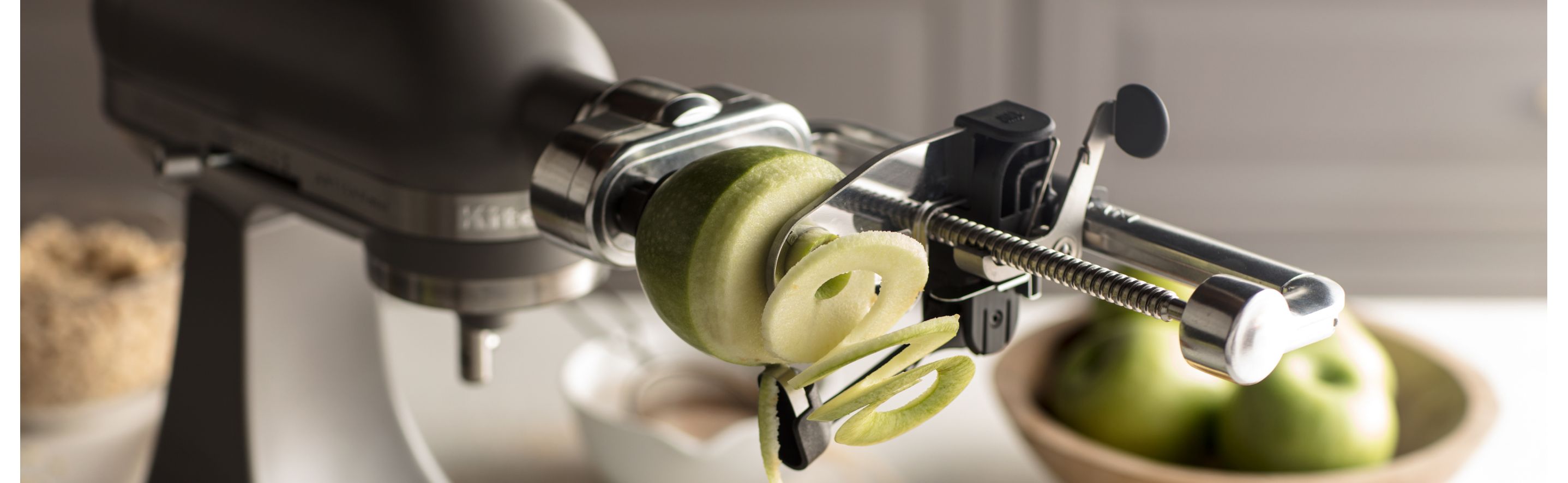 Green, Granny Smith apple being spiralized using a KitchenAid® fresh prep attachment.
