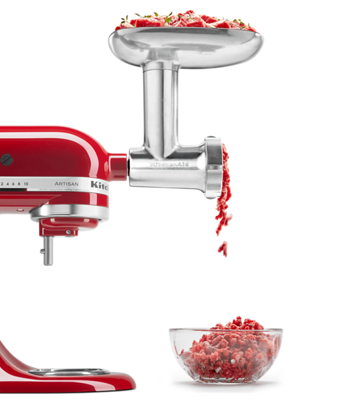 Fresh, cubed meat being processed through the grinder attachment with a variety of herbs.