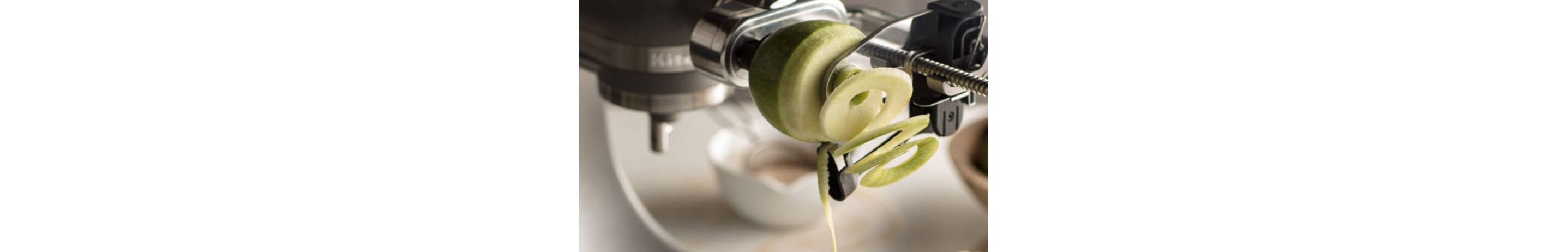 A Spiralizer Attachment spiralizing a green apple.