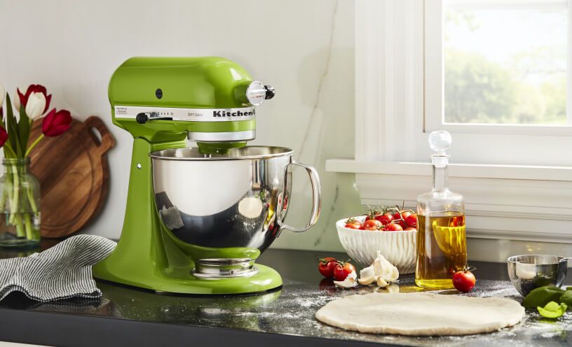 Green Apple KitchenAid® stand mixer on a counter with cherry tomatoes, garlic, olive oil and dough