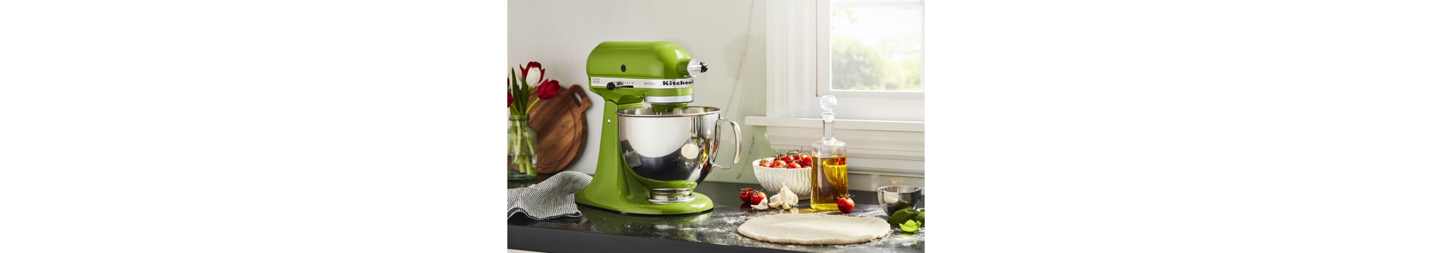 Green Apple KitchenAid® stand mixer on a counter with cherry tomatoes, garlic, olive oil and dough