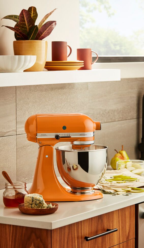 Honey KitchenAid® stand mixer on a counter with fruit, cheese and honey