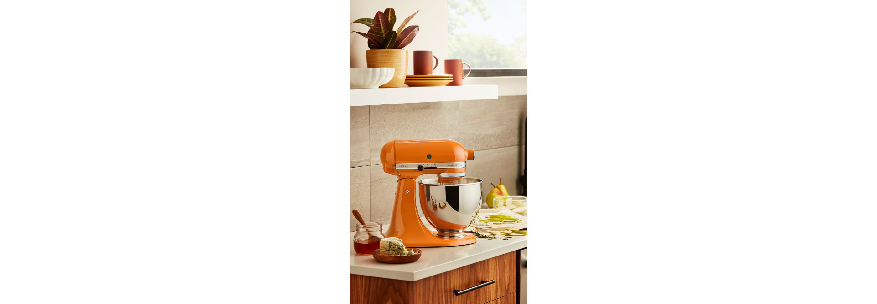 Honey KitchenAid® stand mixer on a counter with fruit, cheese and honey