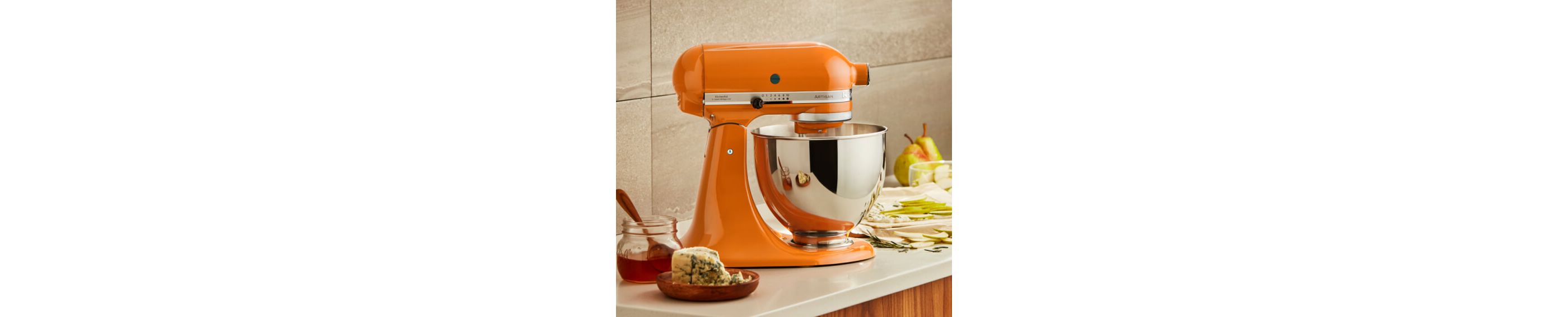 Honey KitchenAid® stand mixer on a counter with fruit, cheese and honey