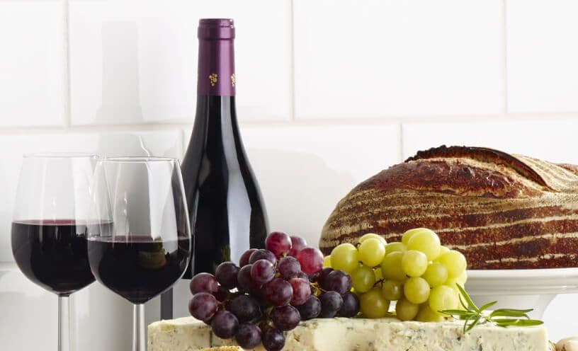Glasses of red wine and a fruit and cheese plate