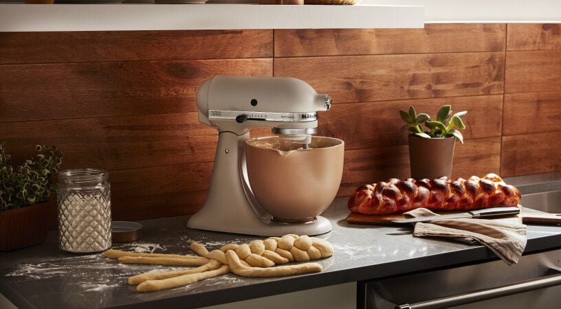 Milkshake KitchenAid® stand mixer on a counter with bread dough and baked bread