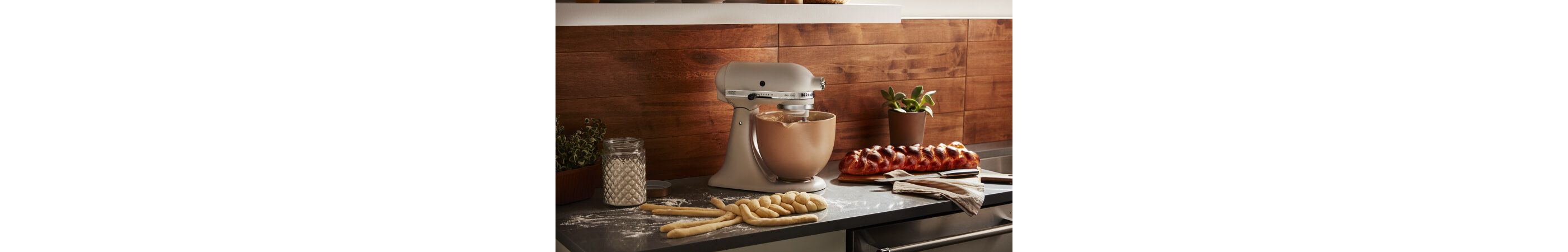 Milkshake KitchenAid® stand mixer on a counter with bread dough and baked bread