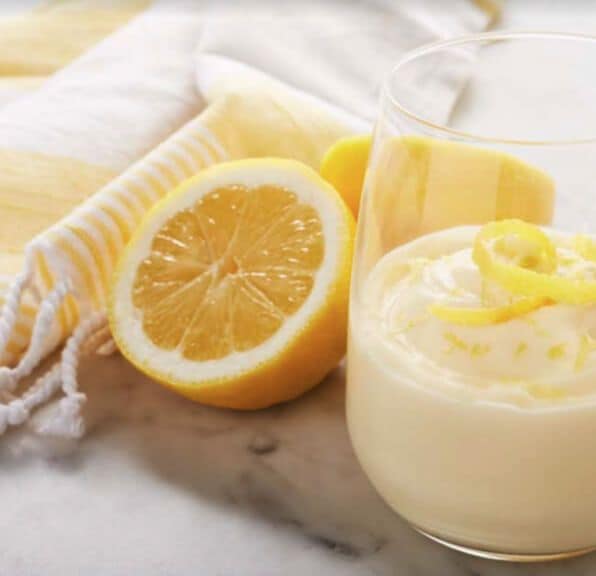 Lemon mousse in a glass next to half a lemon